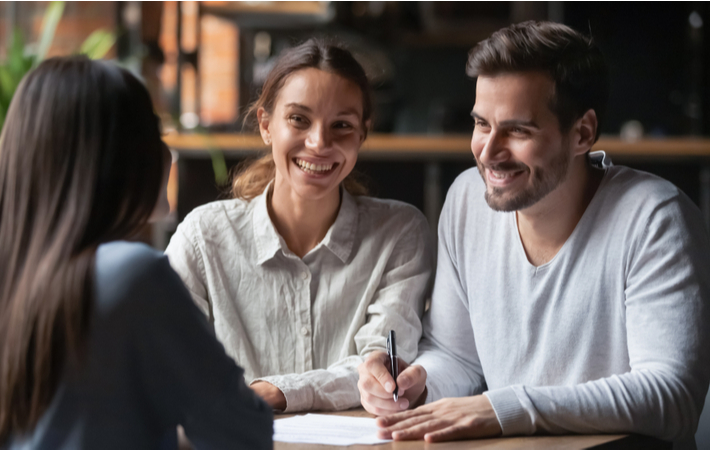 Happy couple talking to lender about steps to catch up with missing mortgage payments