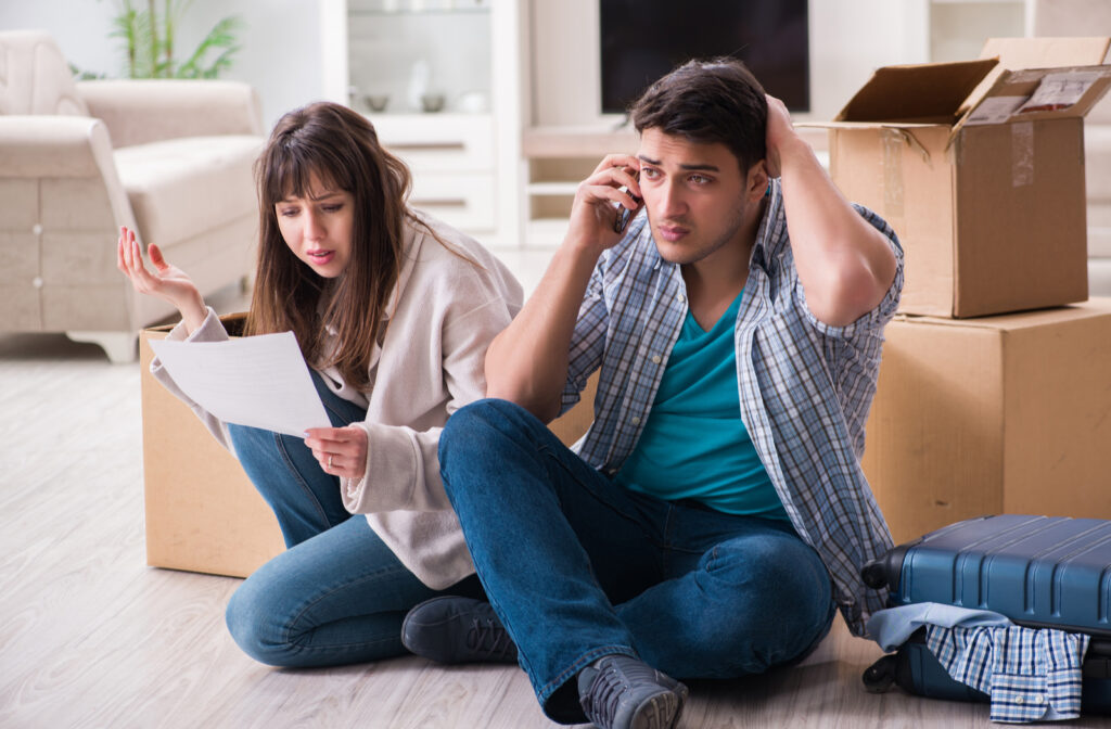 Young couple receiving foreclosure notice letter with boxes in middle of living room of home