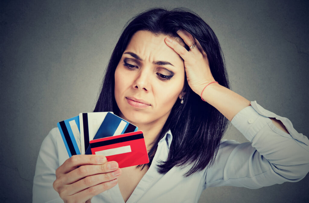 Worried looking women looking at multiple credit cards she has to pay off before the end of the month