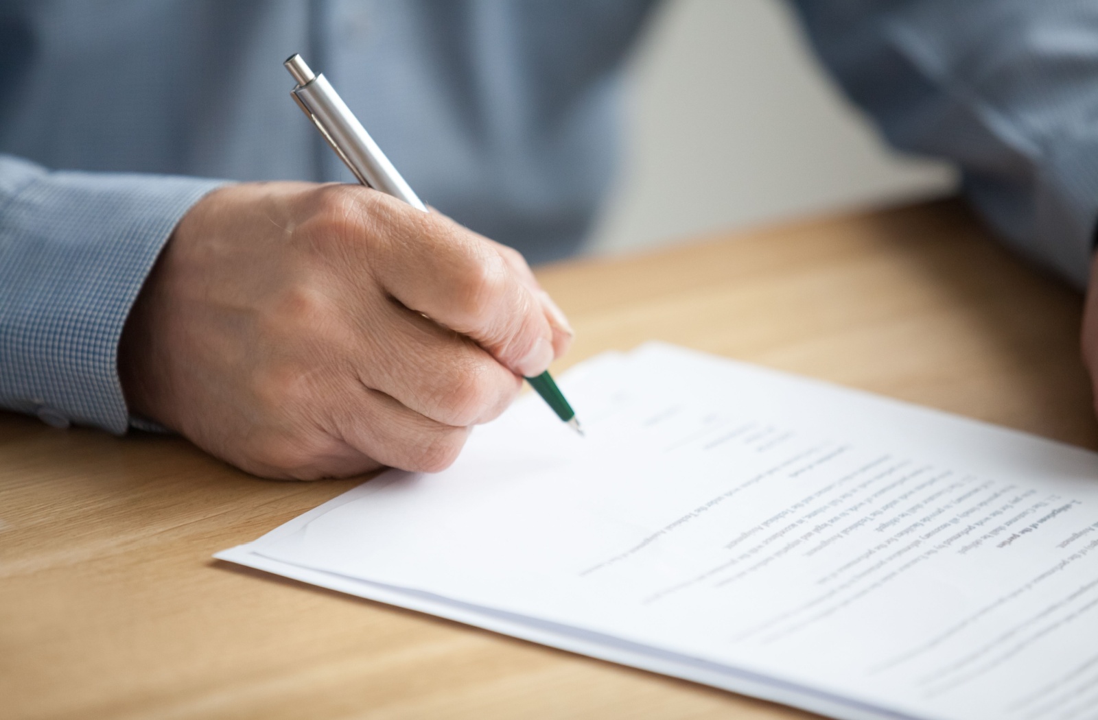 A close-up of a person signing a power of attorney document.