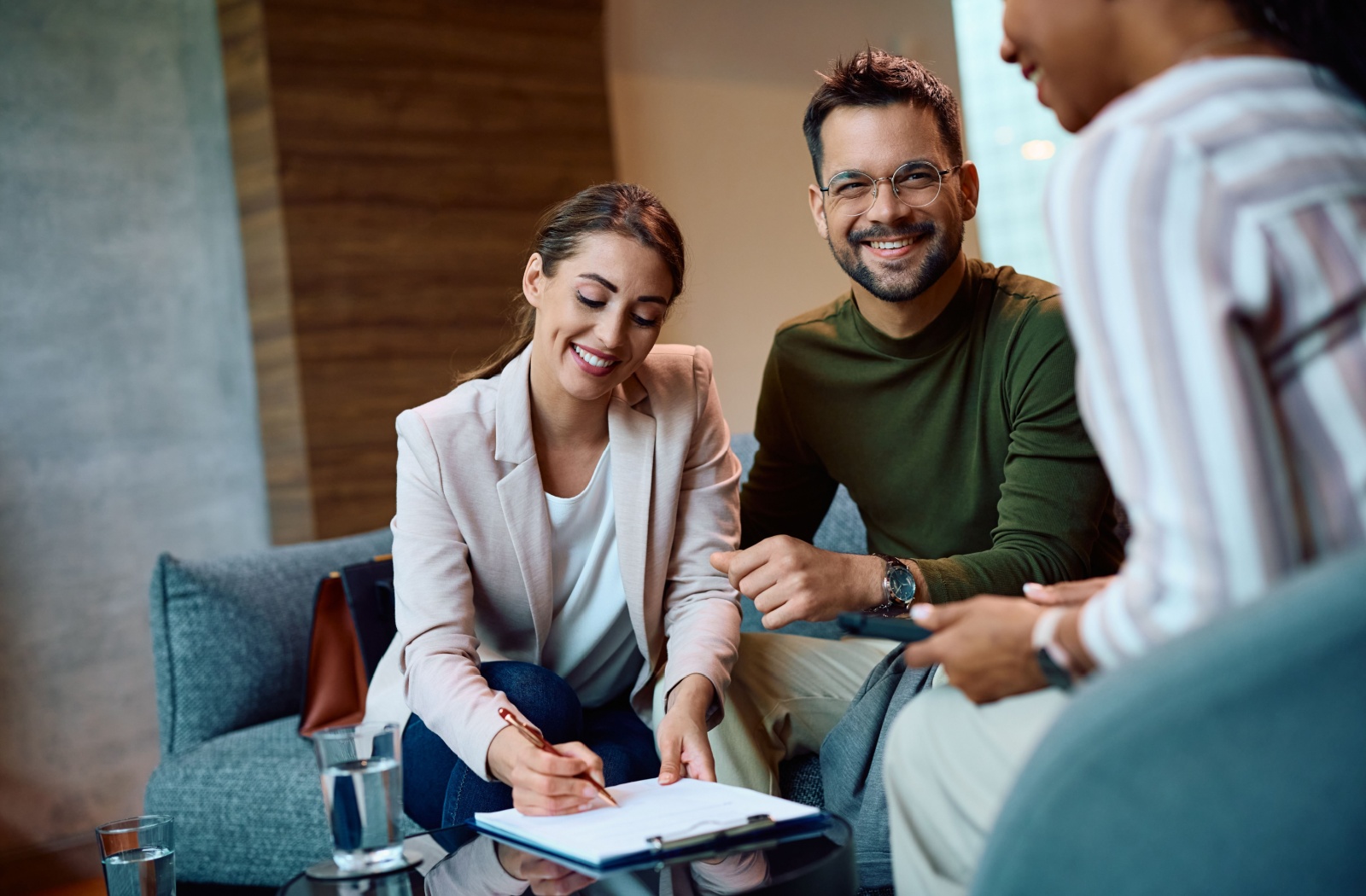 A happy couple signing a debt consolidation document with their financial advisor.