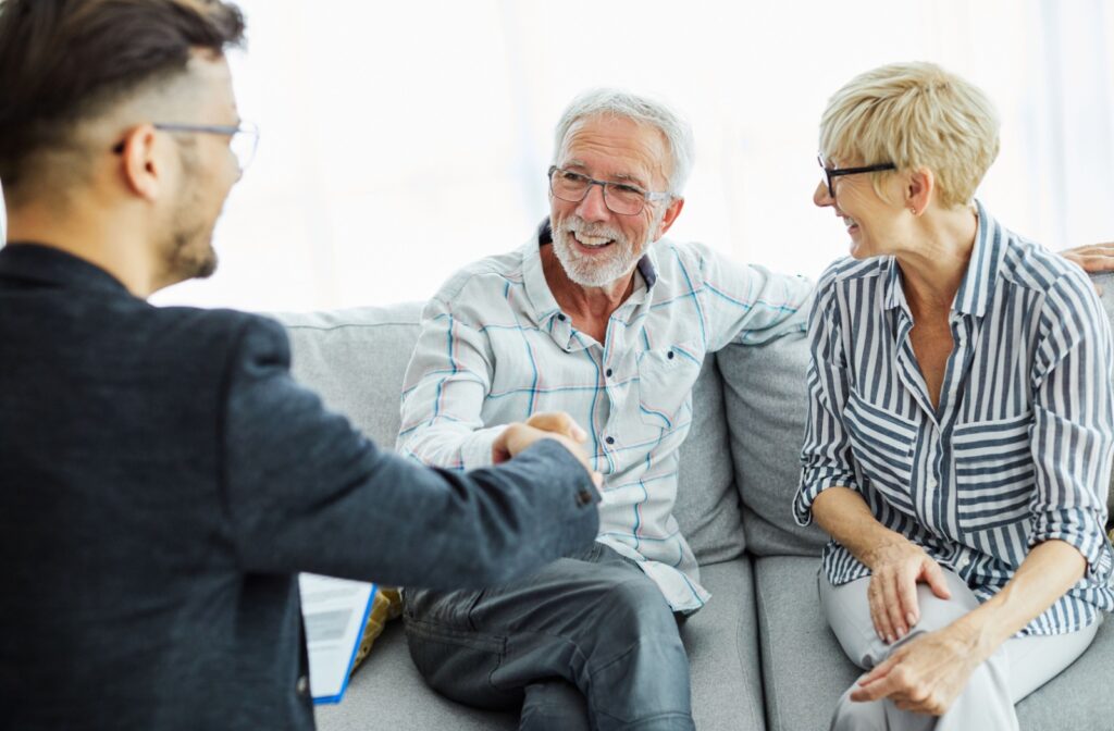 A licensed insolvency trustee shaking hands with a couple sitting across from him after going through credit counselling for debt relief.