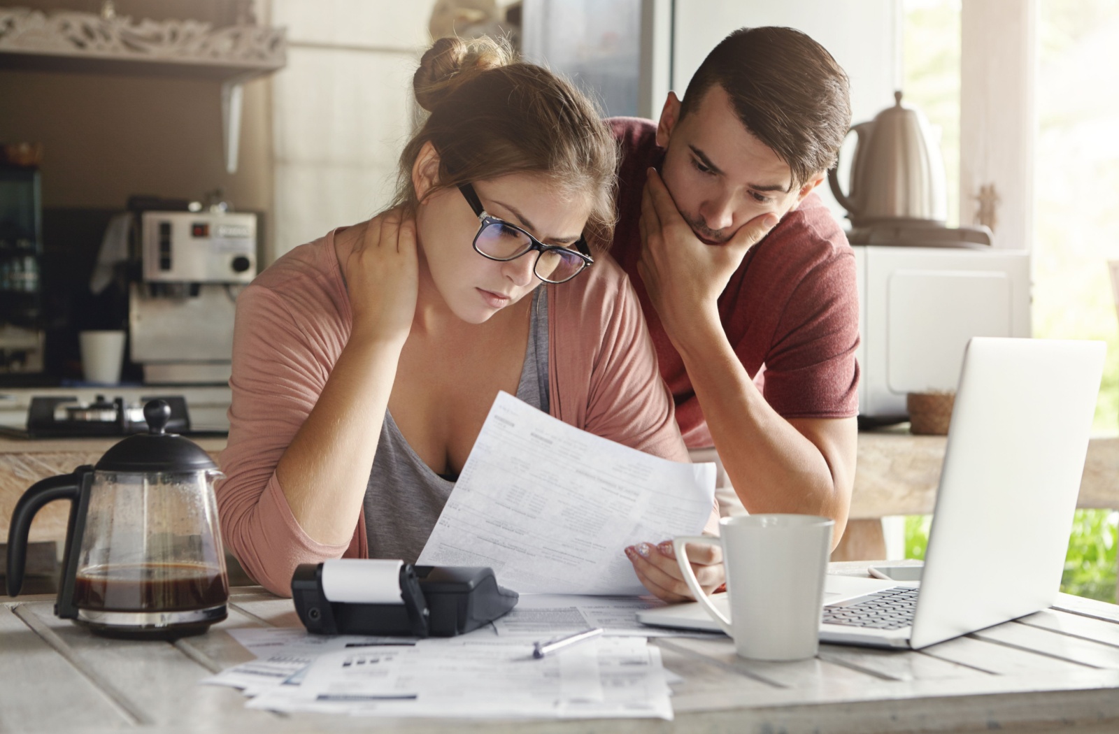 A stressed couple in their kitchen looks over their credit card debt.