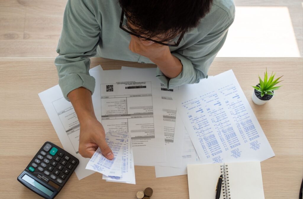 A birds eye view of a person looking over bank statements, trying to figure out what to do with debt after someone if their life has passed.