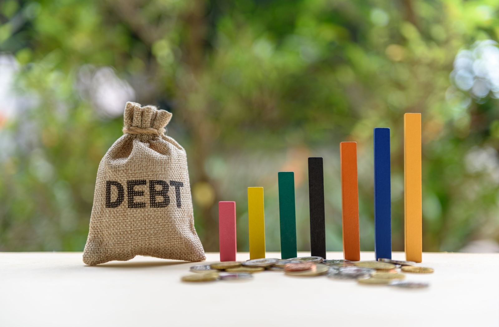 A bag labelled debt beside a graph increasing, representing how a person's debt is increasing.