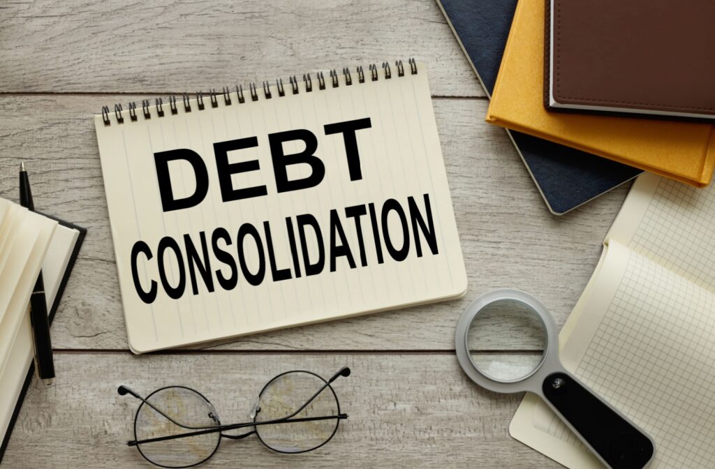 A notebook sitting on a desk with the words "debt consolidation" written on it.